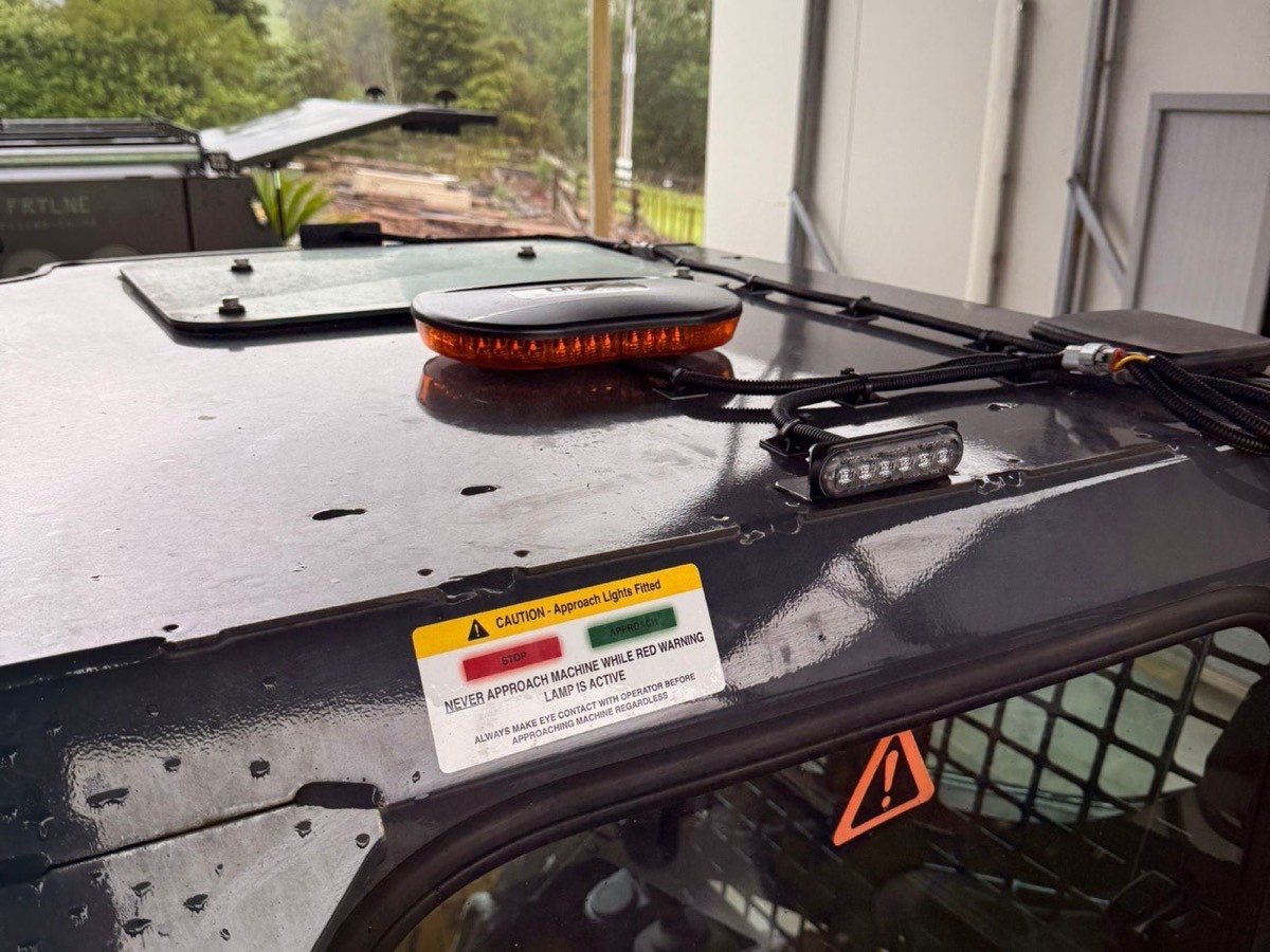 Approach warning lights and amber mini light bar fitted to a loader roof, with caution decal