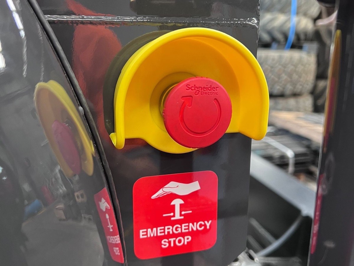 Guarded emergency stop button installed on a forklift, with emergency stop decal