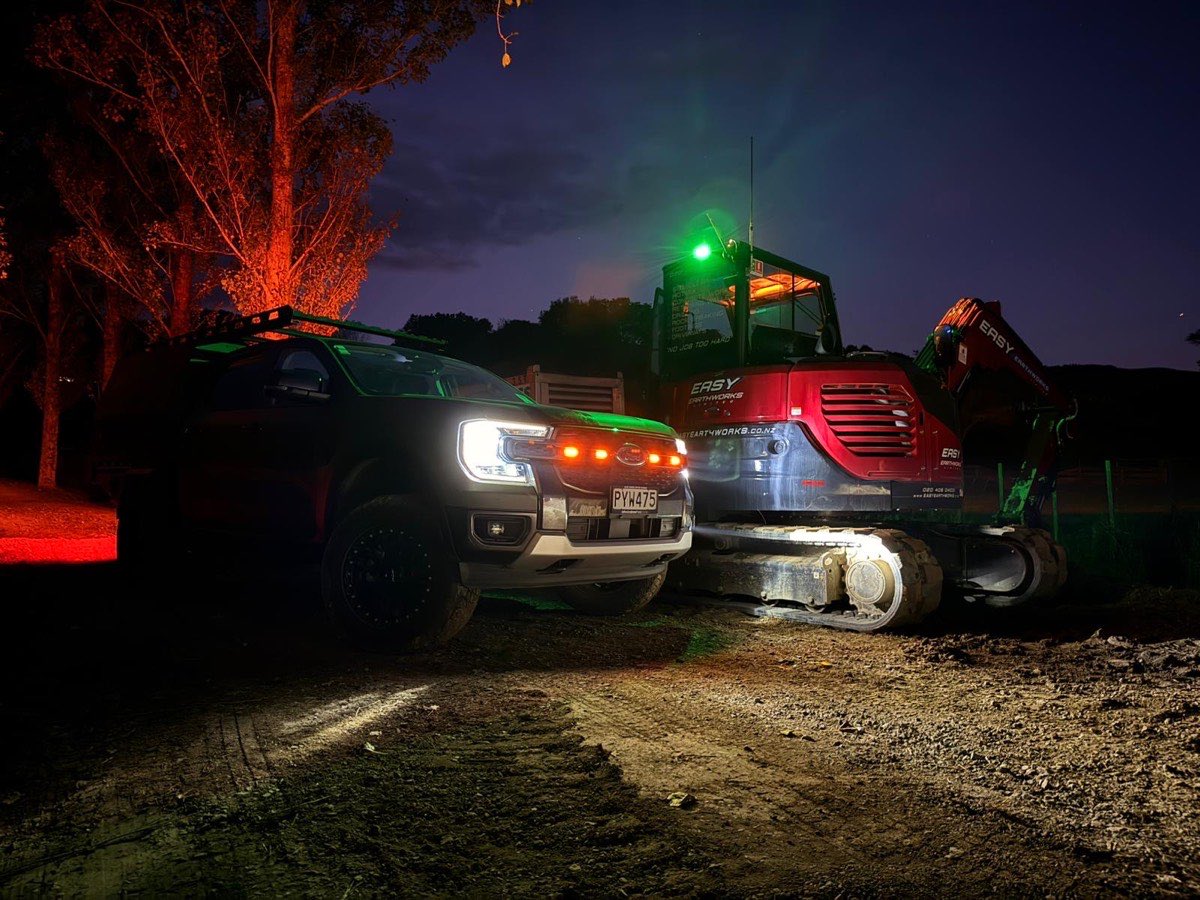 Frontline ute and an excavator at night with freshly fitted green beacon, amber strobes and work lights running